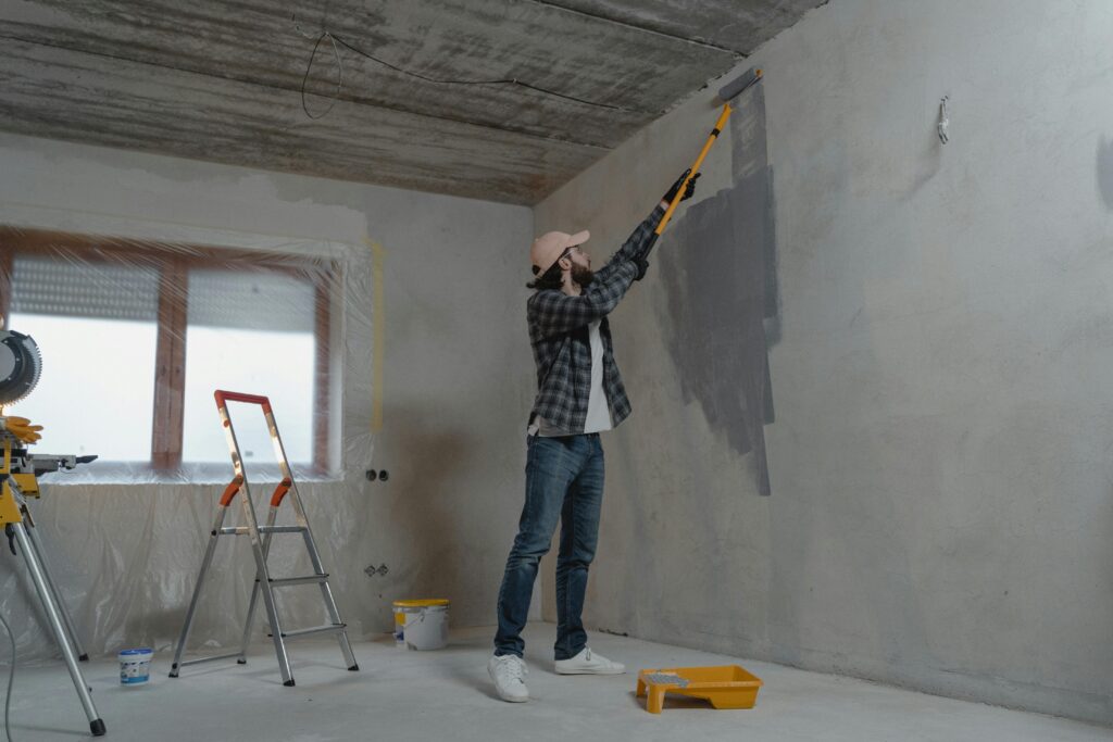 Professional house painter applying premium interior wall paint with full surface protection in Singapore